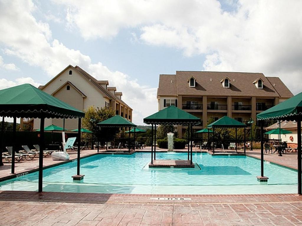 a large swimming pool with green umbrellas in front of a building at French Quarter Resort in Branson