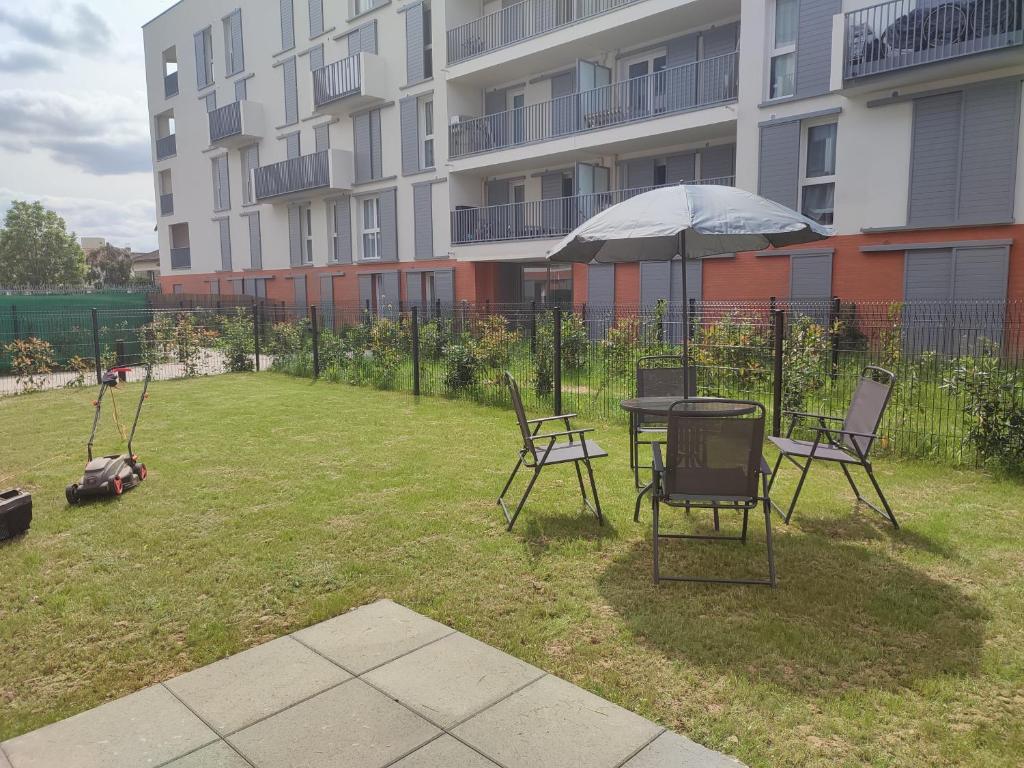 eine Terrasse mit Tisch, Stühlen und Sonnenschirm in der Unterkunft Chambre à 25 min de Paris - appartement partagé in Gonesse