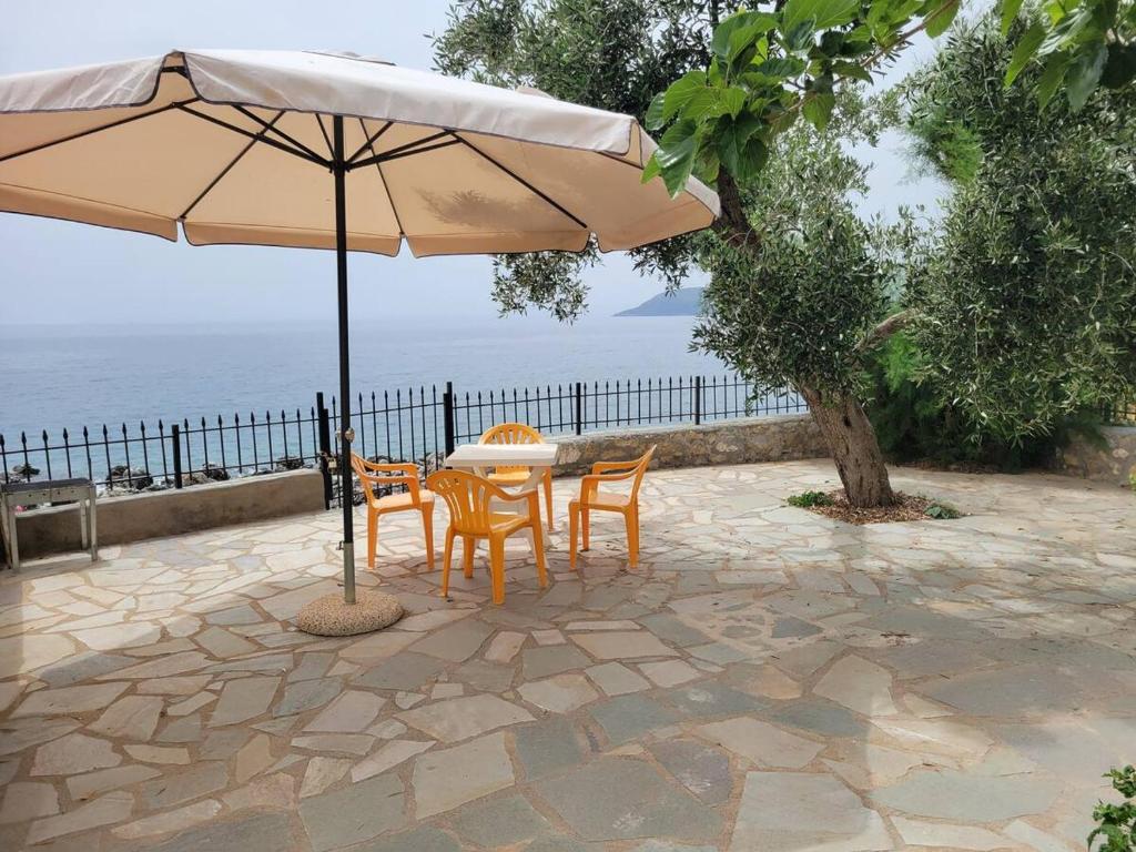a table and chairs under an umbrella on a patio at Seafront Villa Fay in Kardamili