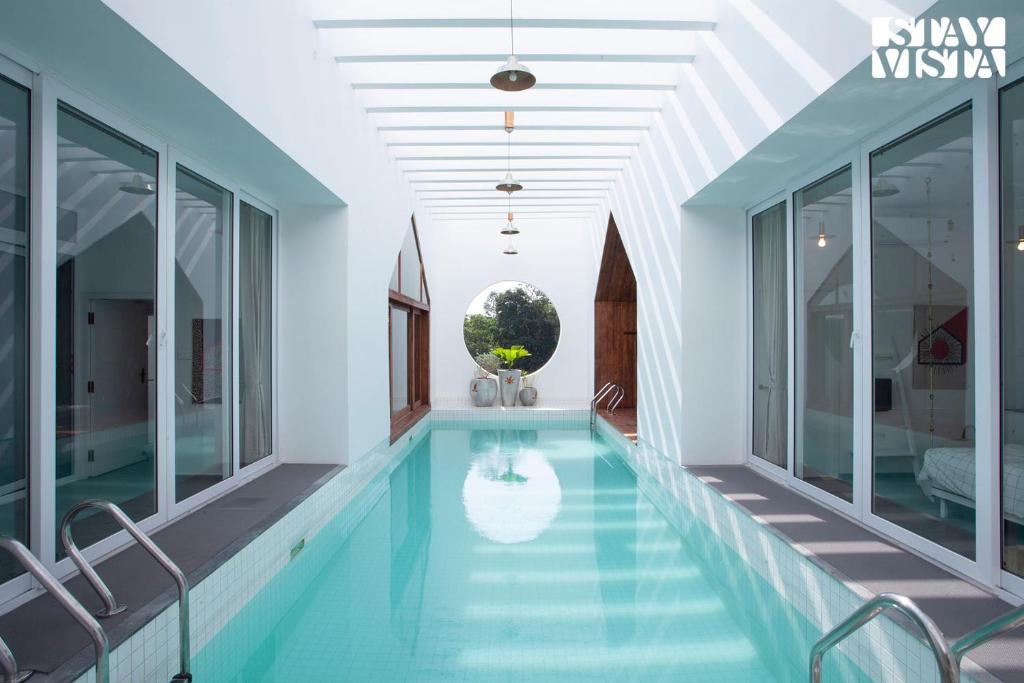 马迪凯里StayVista at Reflection by The Woods - Breakfast Included - Luxury Villa的玻璃墙房子内的游泳池