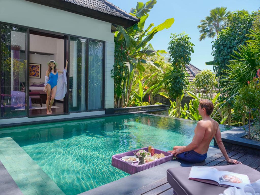 a man sitting on the edge of a swimming pool in a villa at The Ayu Kintamani Villa at Toya Devasya in Kintamani