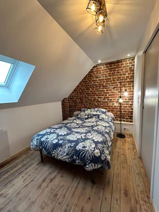 une chambre avec un lit et un mur de briques dans l'établissement Appart 4 personnes Béthune Centre, à Béthune