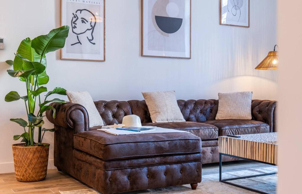 - un salon avec un canapé en cuir brun et un pouf dans l'établissement 65m2 Cosy 2 chambres - 10mn palais & plages, à Cannes