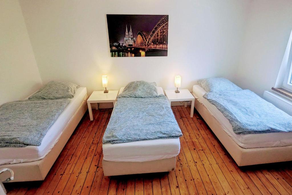 two beds in a room with two lamps on tables at Apartment Köln Weidenpesch in Cologne