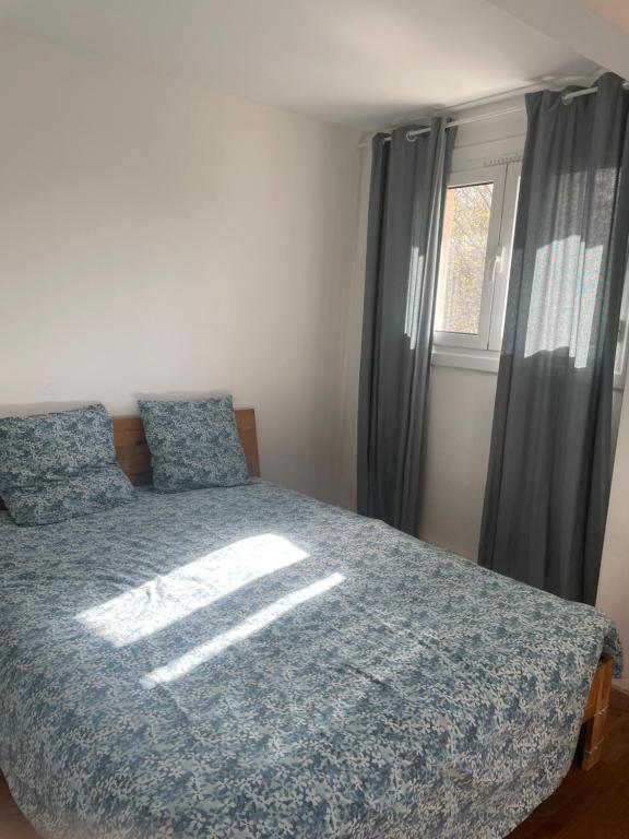 une chambre avec un lit avec une couette bleue et une fenêtre dans l'établissement Agréable chambre, à Ussac