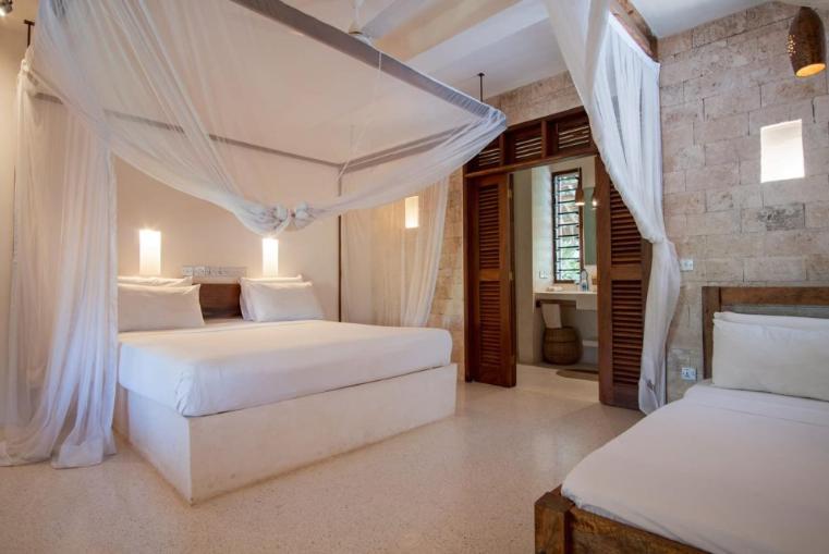 1 dormitorio con 2 camas con cortinas blancas en Palm Garden Boutique Hotel en Watamu