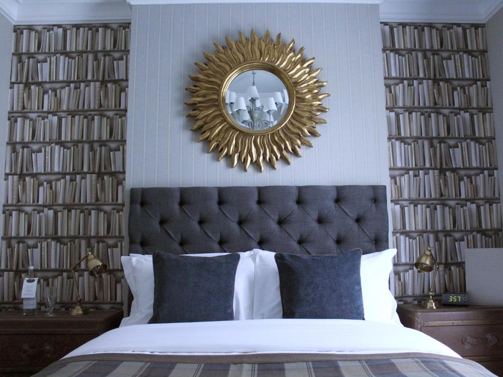 a bedroom with a large gold mirror above a bed at The One Tun Pub & Rooms in London