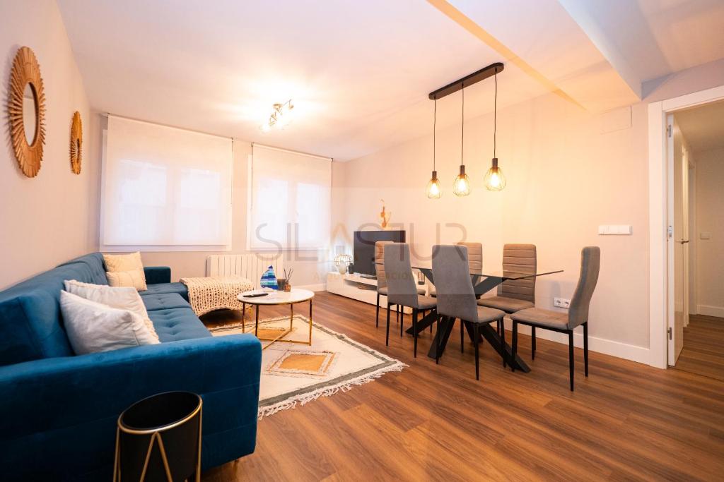 een woonkamer met een blauwe bank en een eetkamer bij Mar De Poniente Apartamento in Gijón