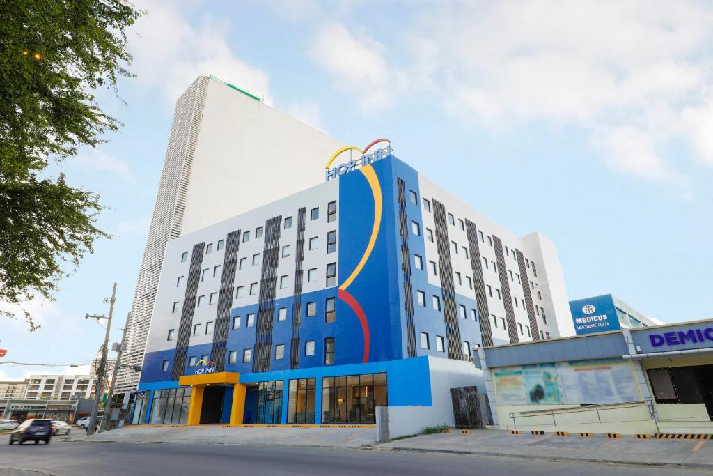 a blue and white building with a tall building at Hop Inn Hotel Iloilo in Iloilo City
