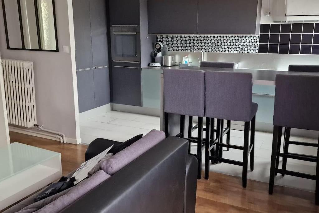 Una sala de estar con un sofá y una cocina. en Refuge Urbain Chic avec Balcon, en Saint Lo