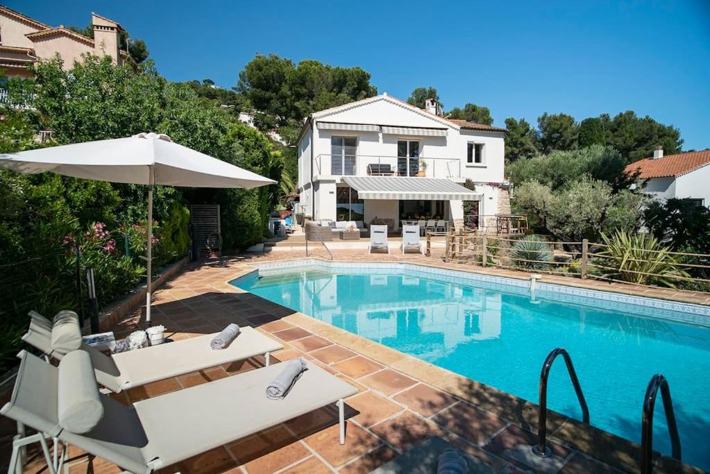 une piscine avec des chaises et un parasol ainsi qu'une maison dans l'établissement Villa NOSSÌ BÈ, à Carqueiranne