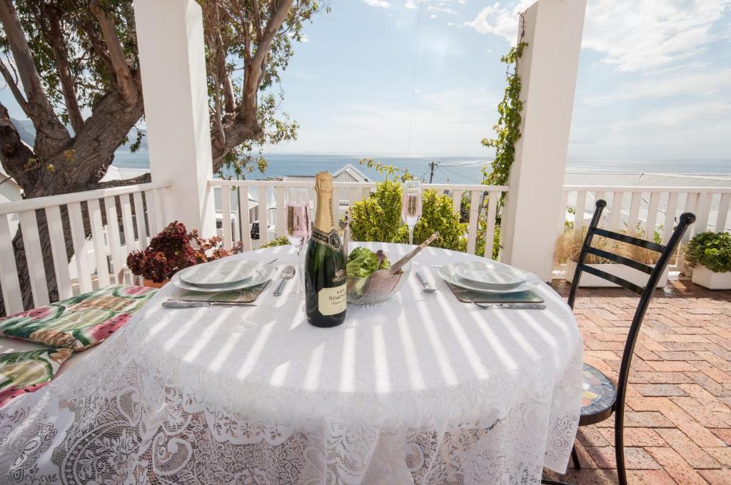 a white table with a bottle of wine on a patio at Mermaid Rock Cottage in Cape Town