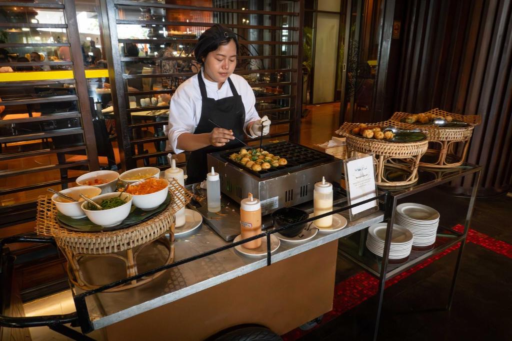a woman standing in a kitchen preparing food at lebua at State Tower in Bangkok