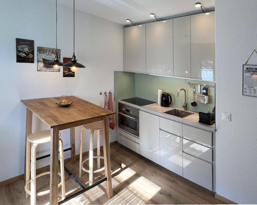 una cucina con mobili bianchi e un tavolo di legno di Chalet Oasis - Your Alpine Hideaway a Bürglen