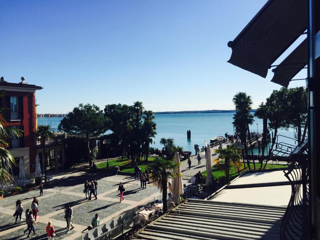 a group of people walking on a sidewalk next to the water at Le Rêve B&B - Lake view rooms in Sirmione