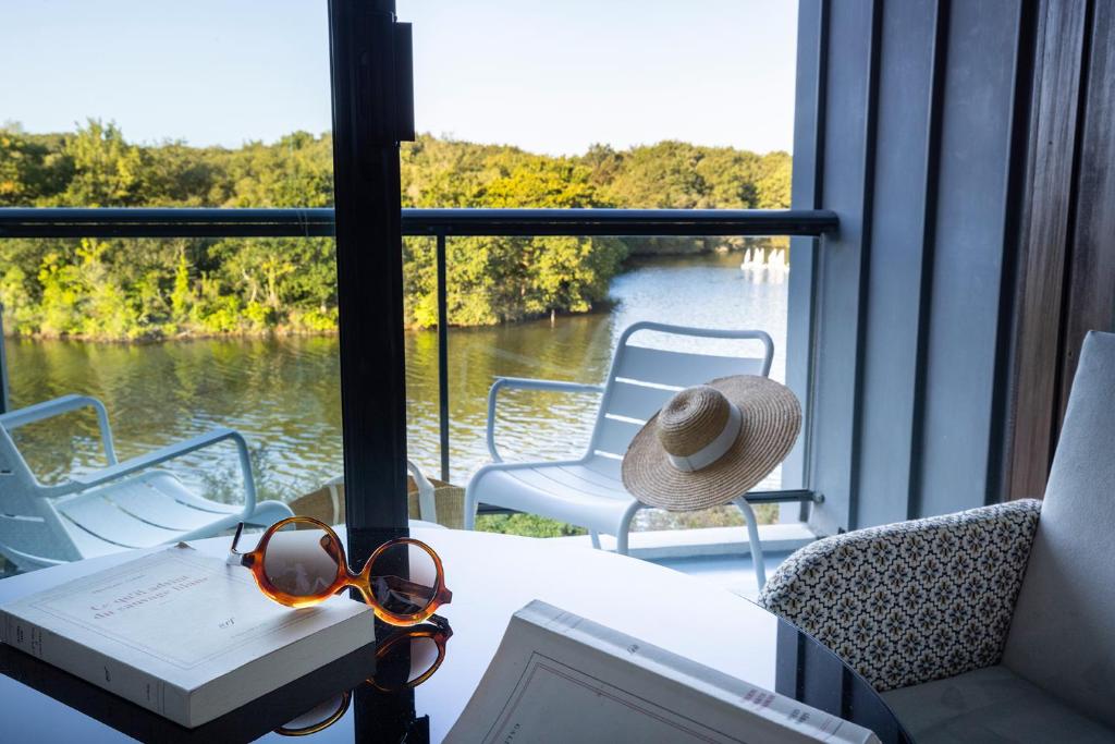 a table with sunglasses and a hat and a laptop on a balcony at Best Western Plus Hotel les Rives du Ter in Larmor-Plage