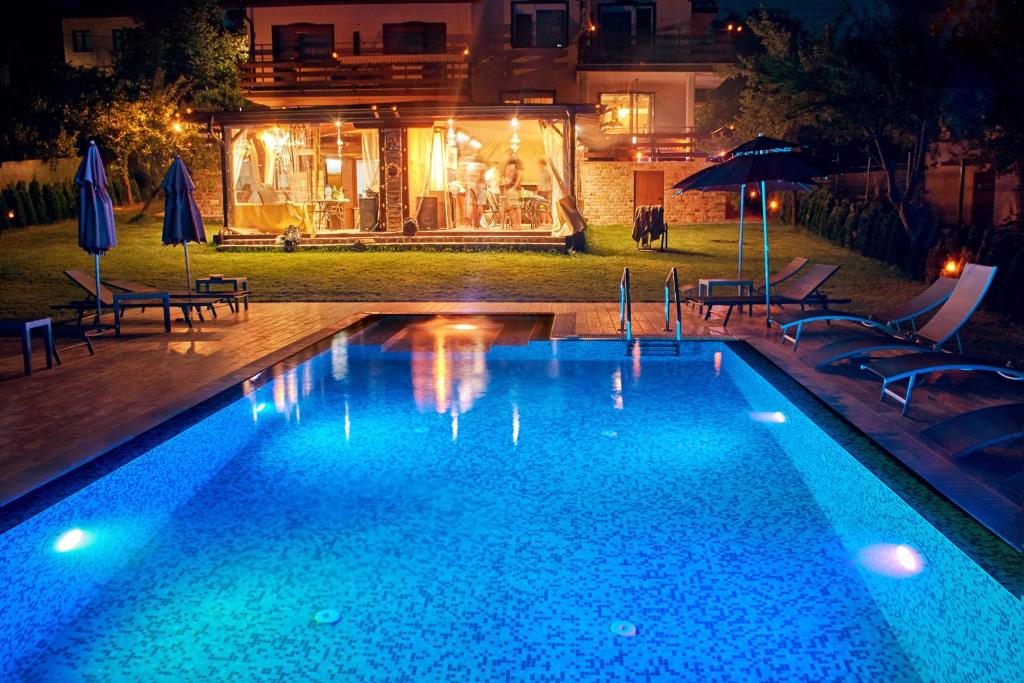 a swimming pool with chairs and umbrellas at night at Sokol i Kalina spa in Pchelin