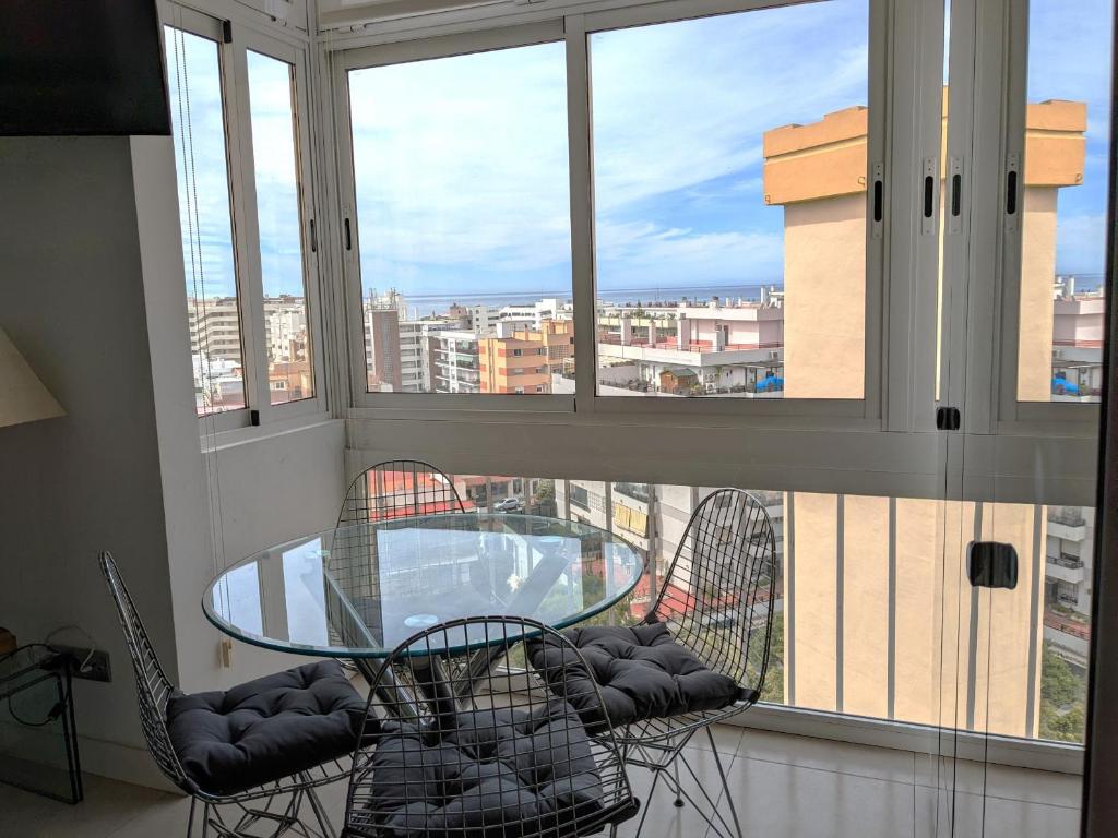 einen Glastisch und Stühle in einem Zimmer mit Fenster in der Unterkunft Apartamentos con vistas y terraza en Marbella in Marbella