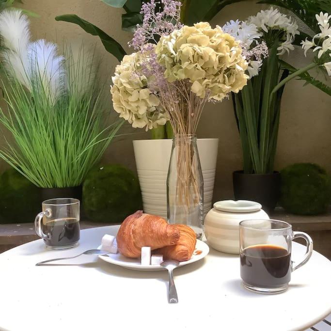une table avec une assiette avec un croissant, du café et des fleurs dans l'établissement Charming studio apartment, à Avignon