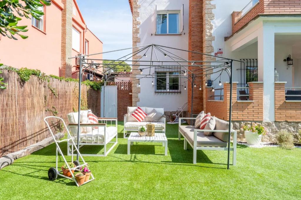 a garden with a swing and chairs on the grass at Casa a 50 metros de la playa in Comarruga