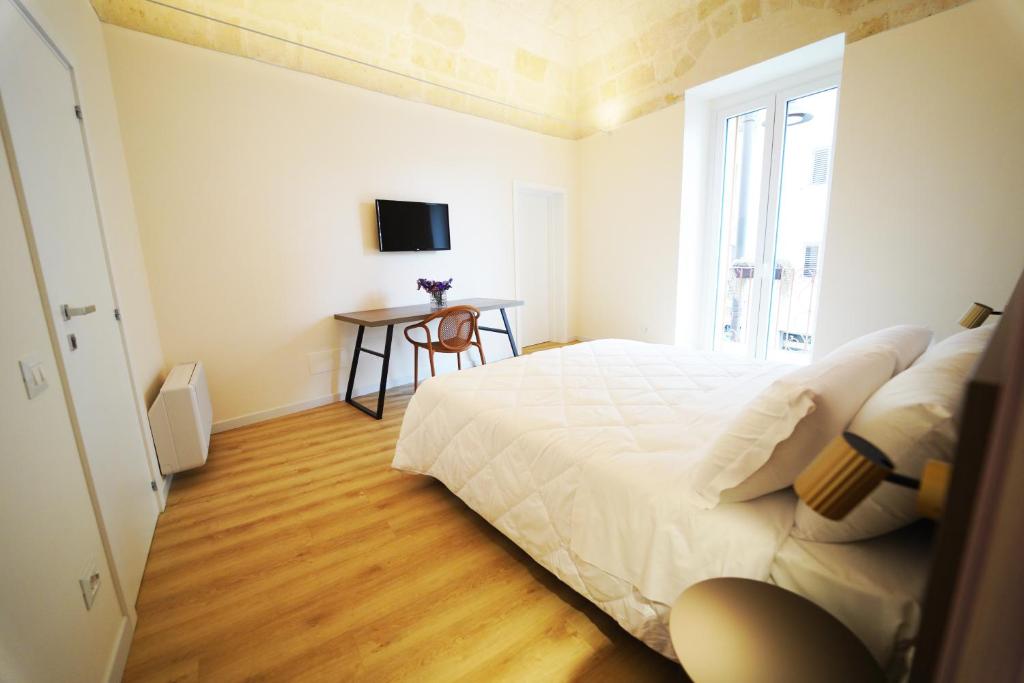 een slaapkamer met een wit bed en een tafel bij La chicca in Matera