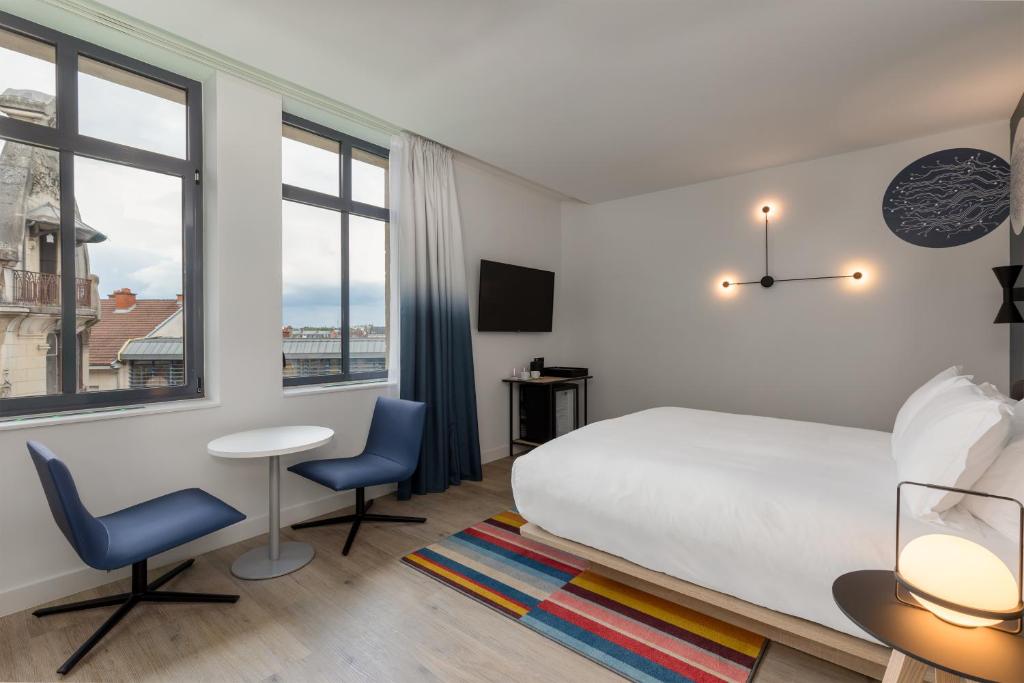 ein Hotelzimmer mit einem Bett und einem Tisch und Stühlen in der Unterkunft Aloft Hotel, By Marriott in Dijon