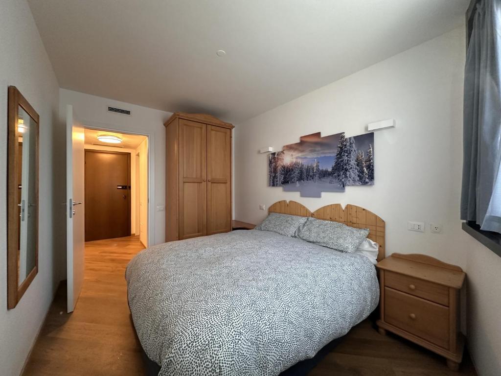 a bedroom with a bed and a wooden night stand at La Stella Bilocale con balcone in Ponte di Legno