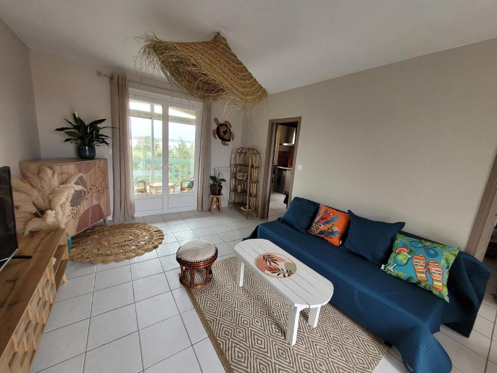 un salon avec un canapé bleu et une table dans l'établissement Le Capestang, à Canet