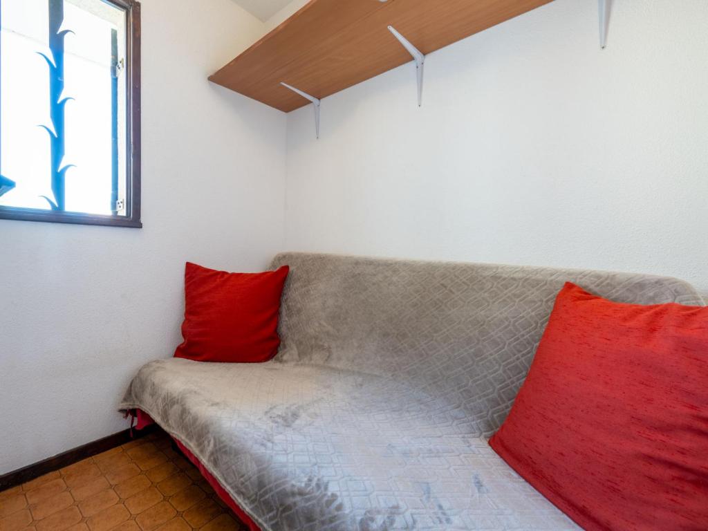 a couch with two red pillows in a room at Apartment Les Eaux Vives 1 &amp; 2-5 by Interhome in Saint Pierre La Mer