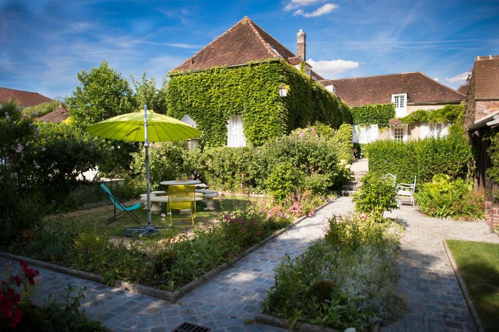 a garden with a table and an umbrella at Aux Charmes de Maintenon in Maintenon