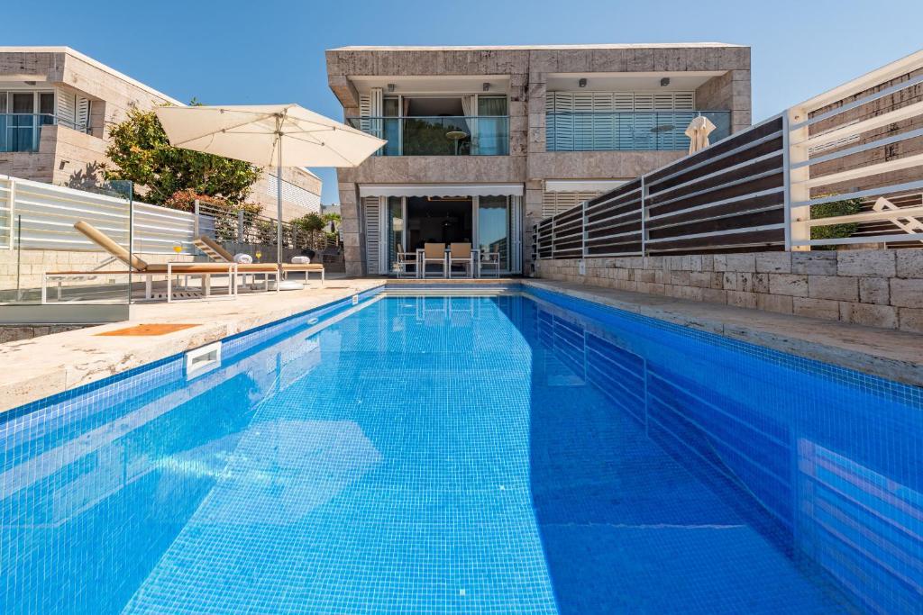a large blue swimming pool with an umbrella at Villa Olea ZadarVillas in Petrcane