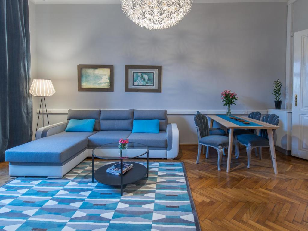 een woonkamer met een blauwe bank en een tafel bij LikeHome Apartment in Zagreb