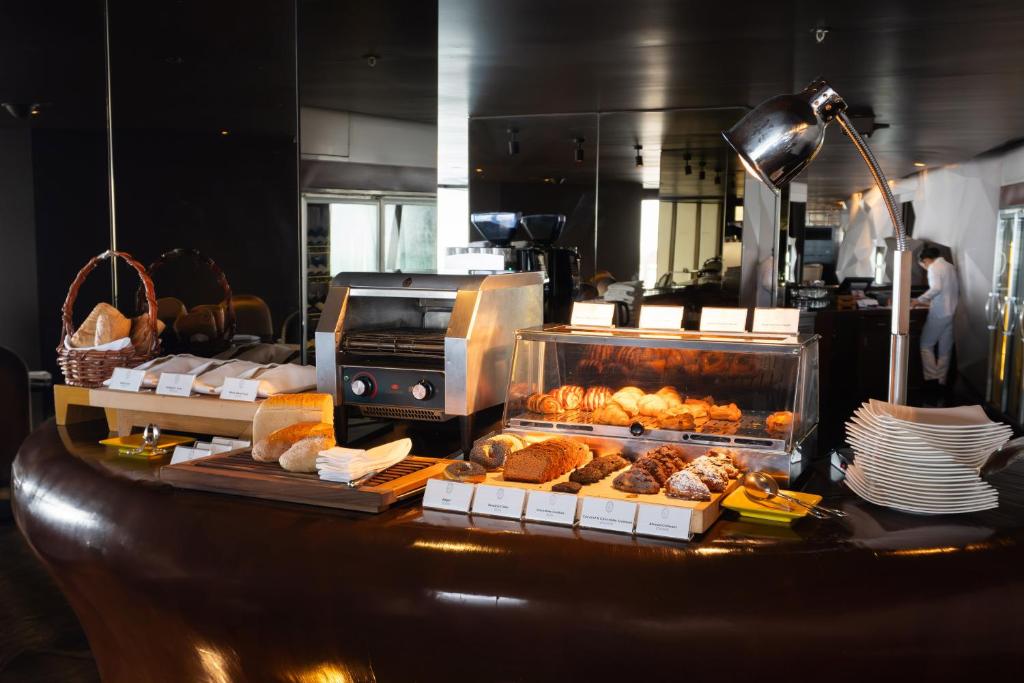 A bakery counter displaying croissants, rolls and pastries under a heated case.