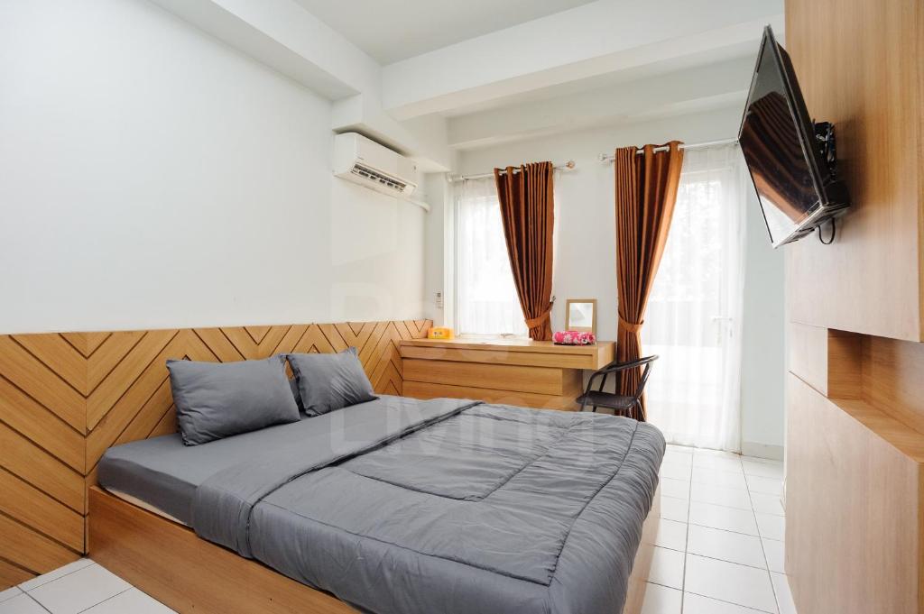 a bedroom with a large bed and a television at RedLiving Apartment Patra Land Urbano - Alfa Rooms Tower East in Bulanbulan
