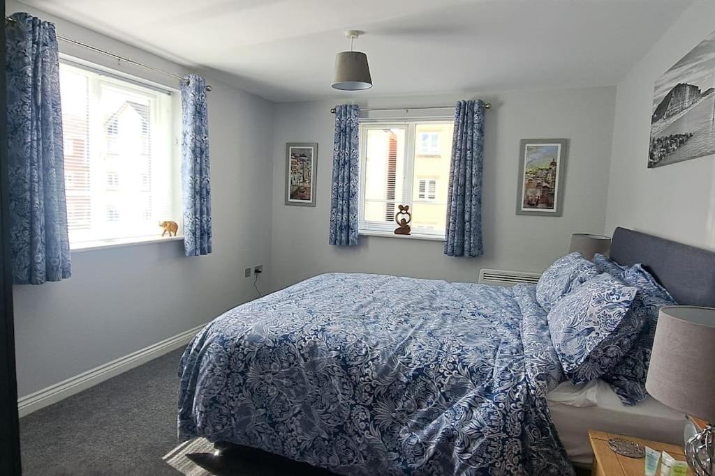 a bedroom with a blue bed and two windows at 2 bedroom apartment in Stratford upon Avon with free onsite parking in Stratford-upon-Avon