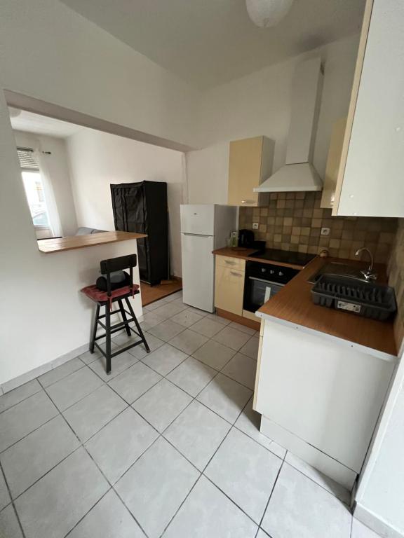 Il comprend une cuisine équipée d'une cuisinière et d'une chaise. dans l'établissement Studio st Quentin centre, à Saint-Quentin