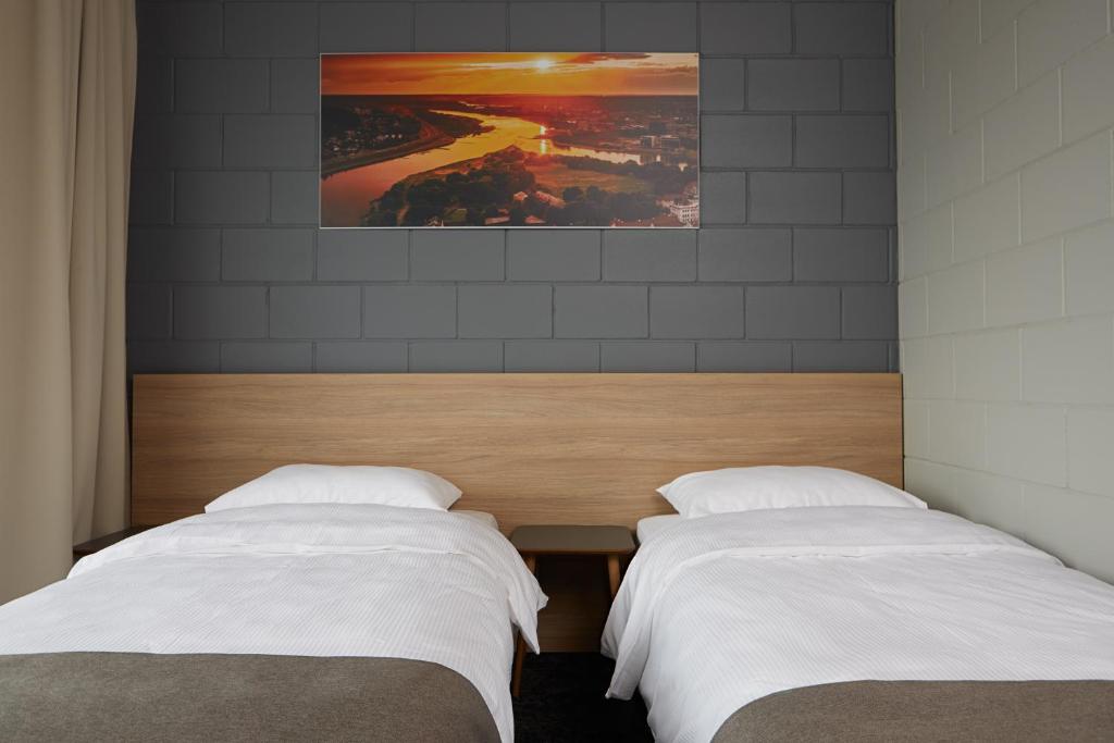 two beds with white sheets in a bedroom at Air Hotel in Karmėlava