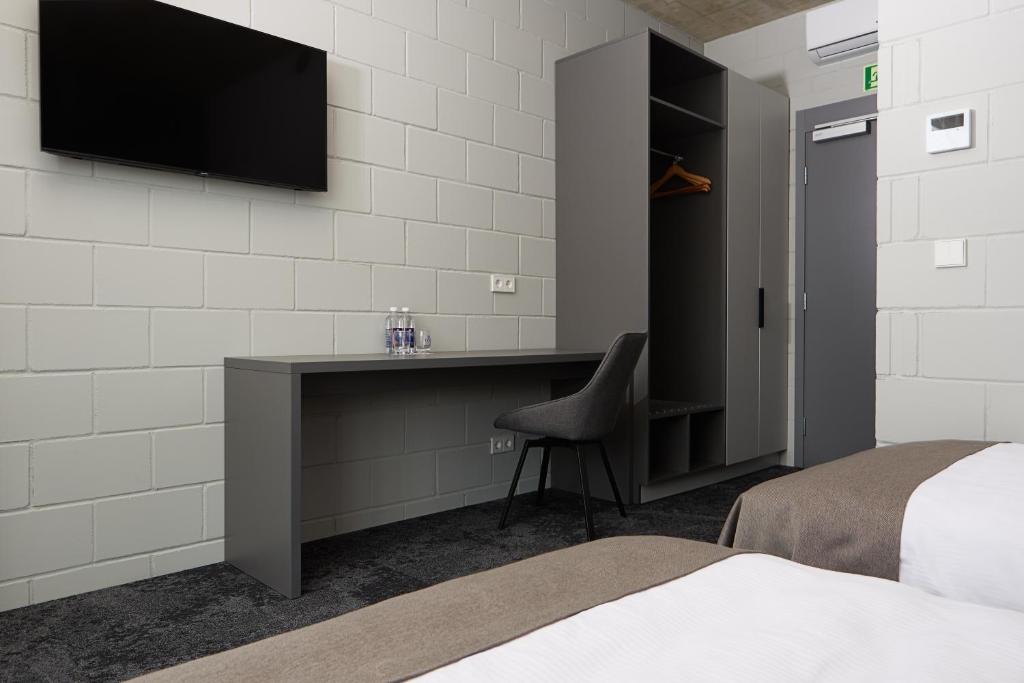 a bedroom with a desk and a television on a wall at Air Hotel in Karmėlava