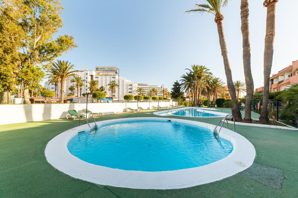 Una gran piscina con palmeras y edificios. en Las Buganvillas, en Roquetas de Mar