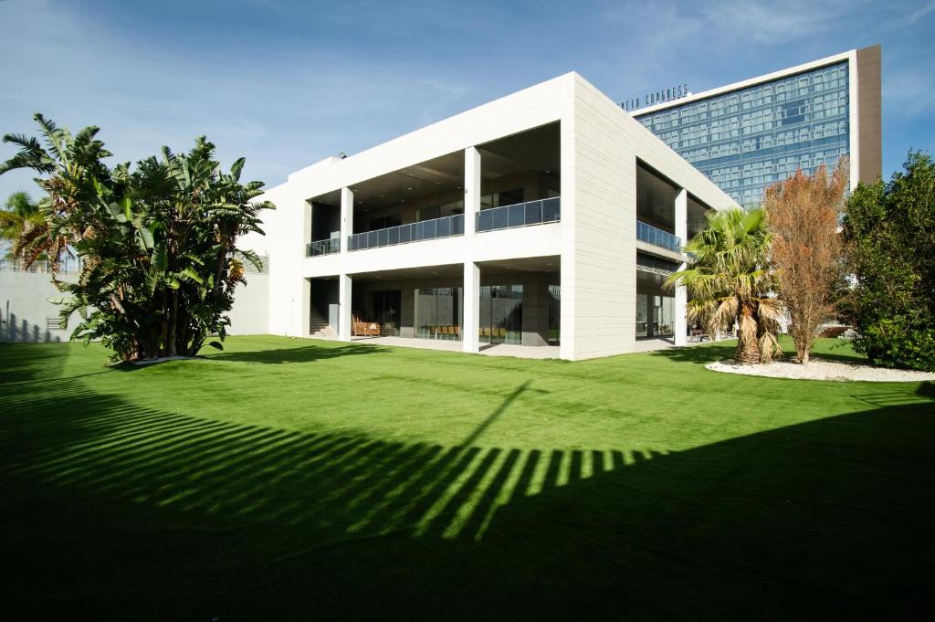 a large white building with a lawn in front of it at AZZ Valencia Congress Hotel & Spa in Paterna