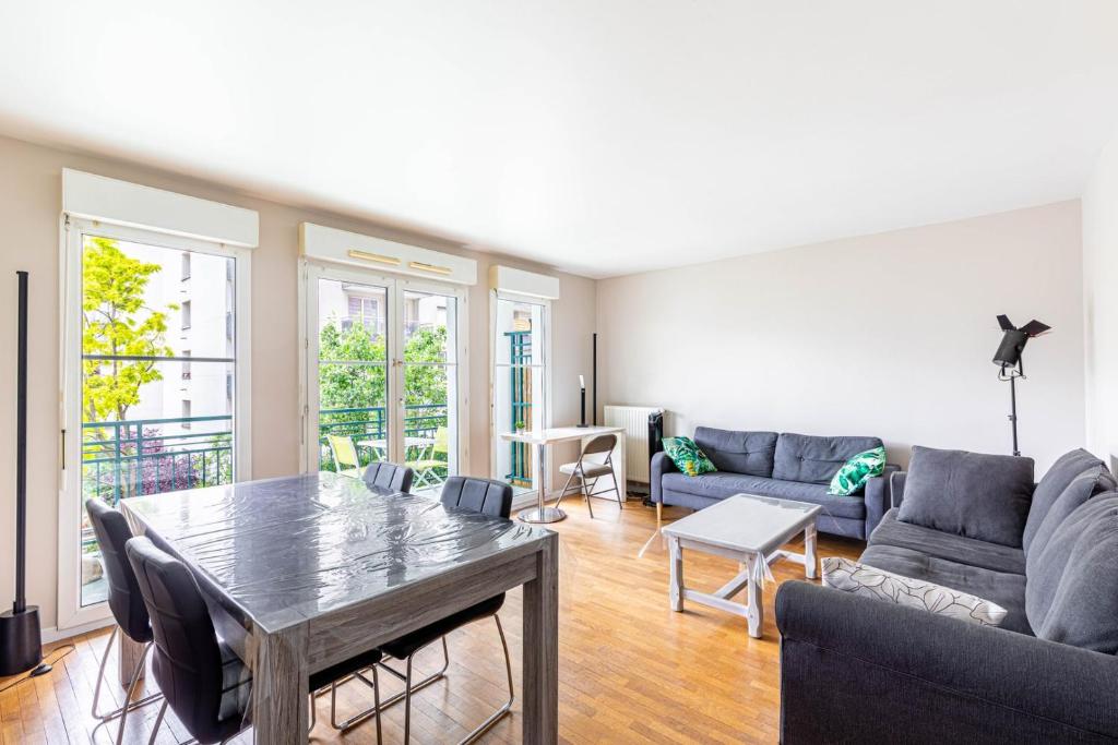 ein Wohnzimmer mit Tisch und Couch in der Unterkunft GuestReady - Havre de Paix à Courbevoie in La Défense