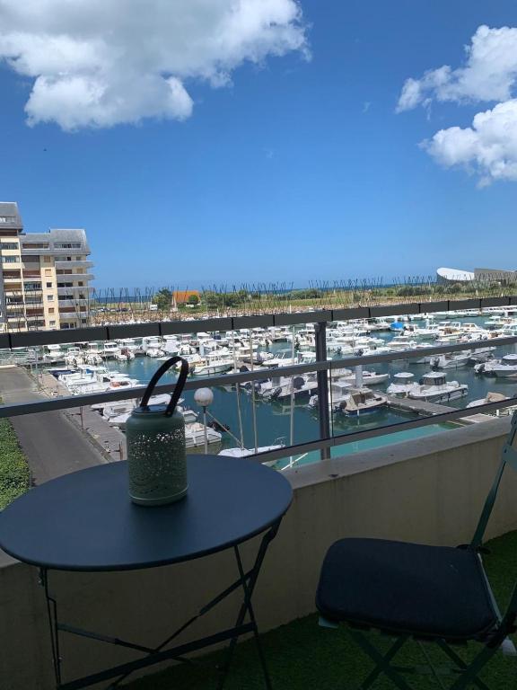 d'une table et d'une chaise sur un balcon avec port de plaisance. dans l'établissement Normandy trip 5 min à pied de la plage, à Courseulles-sur-Mer