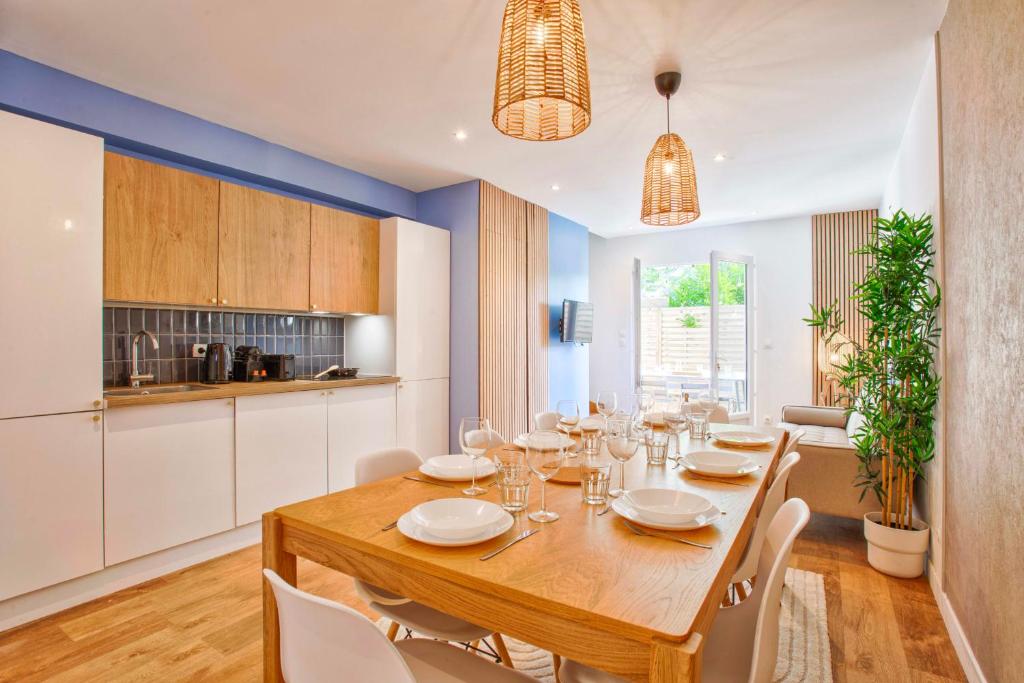 a dining room with a wooden table and white chairs at Charming seaside house in Varaville