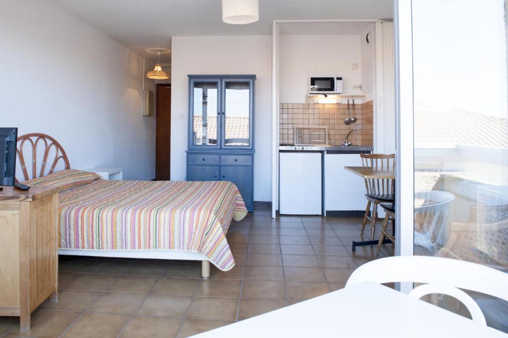 ヴァルラ・プラージュにあるRésidence Créoleの小さなベッドルーム(ベッド1台付)、キッチンが備わります。