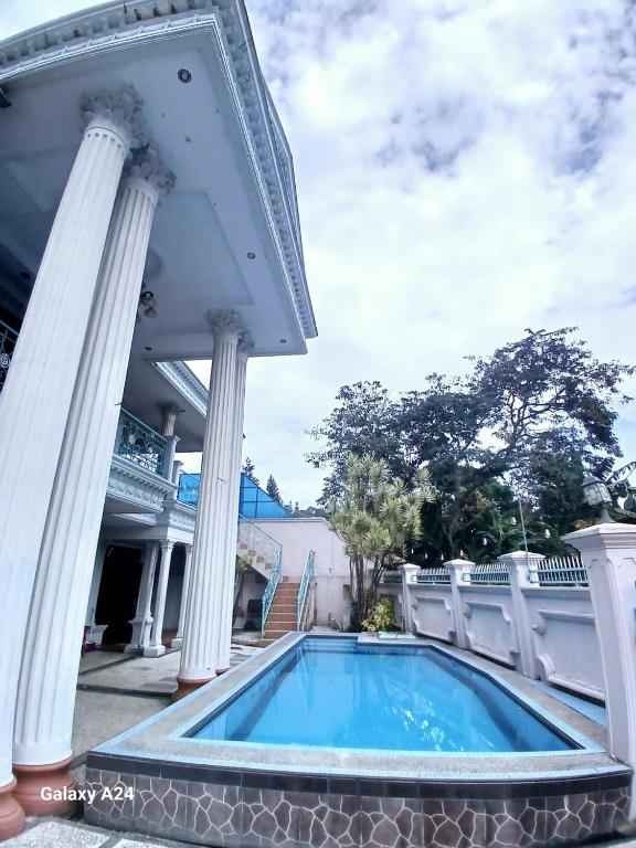 a swimming pool in the middle of a house with columns at Villa Rashensa in Paragajen