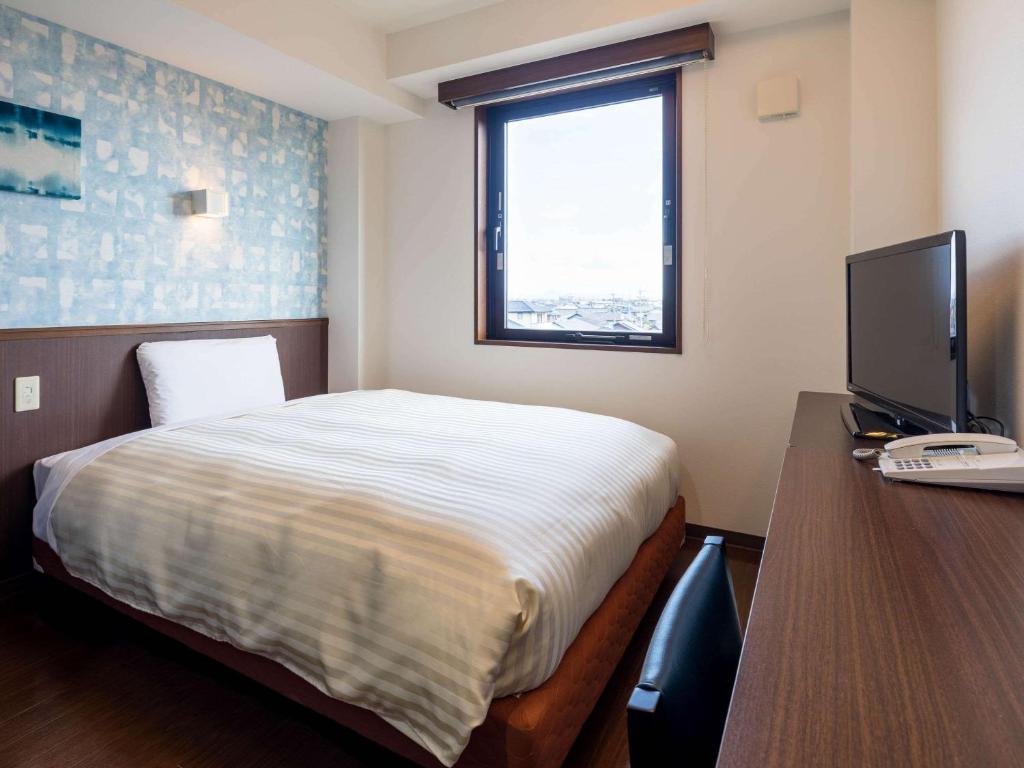 a bedroom with a bed and a desk with a computer at Comfort Inn Ogaki in Ogaki
