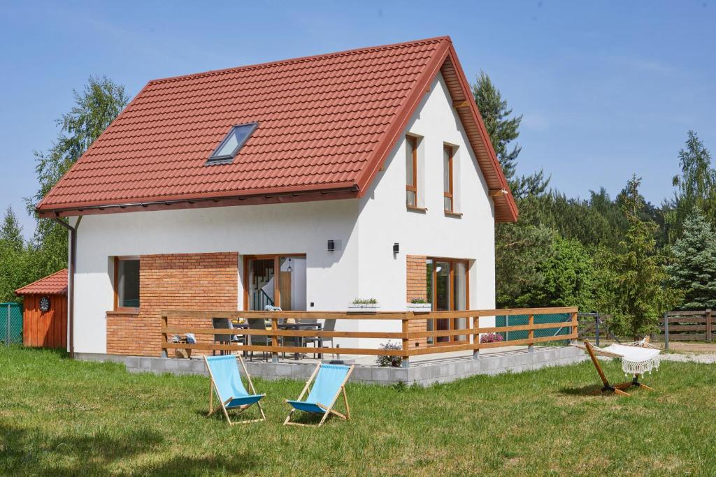 una casa con dos sillas delante en Szczęśliwy Domek 