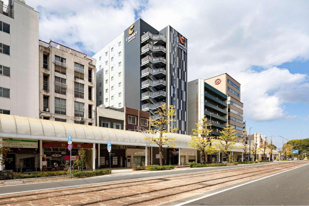 an empty city street with tall buildings and a road at Comfort Hotel Matsuyama in Matsuyama
