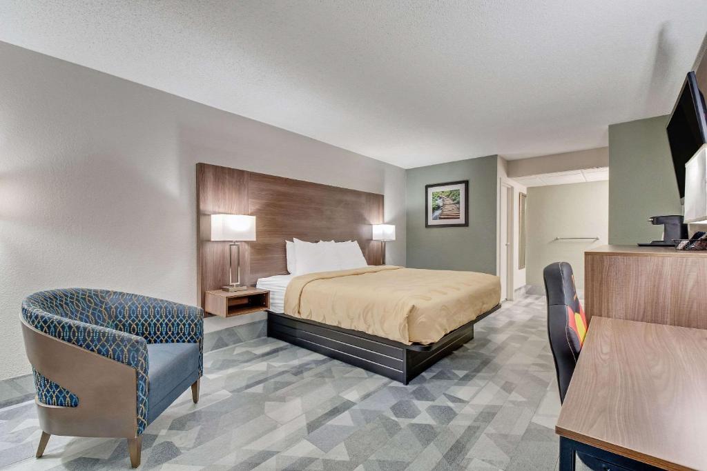 a hotel room with a bed and a chair at Quality Inn in Dalton