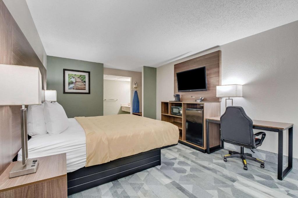 a hotel room with a bed and a desk and a computer at Quality Inn in Dalton